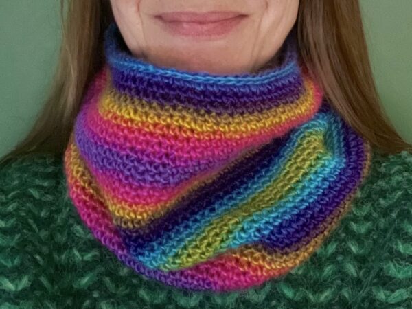 A handmade, close textured, crocheted neck warmer, made using a soft and lightweight acrylic yarn in a mix of bright rainbow inspired colours.