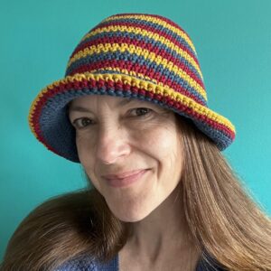 A hand crocheted bucket style hat, made using 100% cotton. It has multi coloured stripes in 3 bright colours, Denim Blue, Mustard yellow and Burgundy. One size.