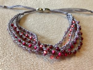 A multi stranded, grey crocheted cotton and glass seed bead bracelet. Using tones of pink glass beads.