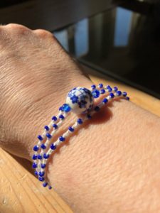 A multi stranded, cream crocheted cotton and glass seed bead bracelet, with a central decorative ceramic flower bead. 