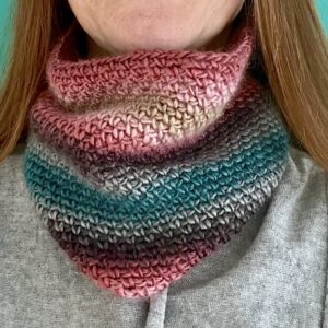 A handmade, close fitting, close textured, crocheted neck warmer, made using a soft and lightweight acrylic yarn in a mix of subtle pink and teal colours.