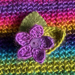 A single crocheted flower in a vibrant purple colour, with vintage button detail and two leaf brooch. Flower made using 100% acrylic with one crocheted leaf and one hand stitched felt leaf. A locking metal brooch fastening on the back. Approximate size 6cm width x 6cm height.