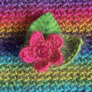 A single crocheted flower in a vibrant pink colour, with vintage button detail and two leaf brooch. Flower made using 100% acrylic with one crocheted leaf and one hand stitched felt leaf. A locking metal brooch fastening on the back. Approximate size 6cm width x 6cm height.