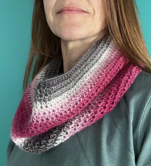 A handmade, soft textured, crocheted neck warmer, made using a soft and lightweight acrylic yarn in a mix of white, grey and pink shades.