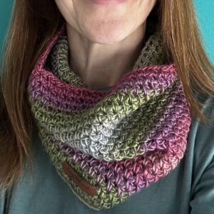 A loose fitting infinity scarf made using a soft and lightweight yarn in a mix of subtle heather colours of Purple, pink, grey, green.