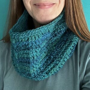 A handmade, soft textured, crocheted neck warmer, made using a soft and lightweight acrylic/wool mix yarn in shades of greens and Blues.
