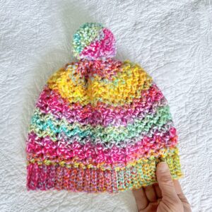 A soft and chunky textured hat with a large detachable bobble. Made in a vibrant mix of rainbow colours, using a very soft and chunky, yet lightweight Acrylic yarn. yarn .
