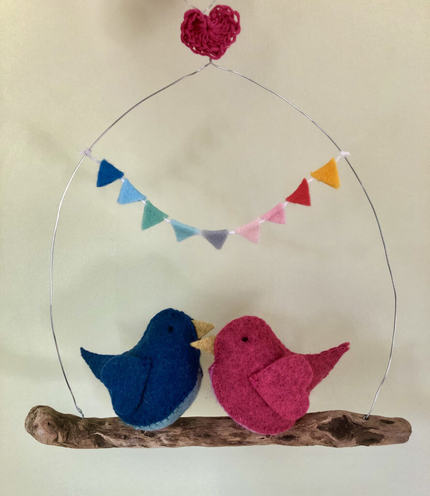 Handmade felt birds and a driftwood hanging perch with felt bunting and crocheted heart.