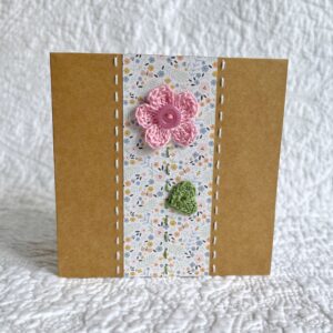 A single crocheted flower and leaf, with a hand stitched border. This small brown card has a blank white insert for your own message, and an envelope is included. Approximate size 10cm x 10 cm. Made using 100% cotton. Eco-friendly, Vegan friendly and fully recyclable.