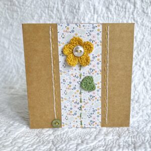 A single crocheted flower and leaf, with a hand stitched border and button detail. This small brown card has a blank white insert for your own message, and an envelope is included. Approximate size 10cm x 10 cm. Made using 100% cotton. Eco-friendly, Vegan friendly and fully recyclable.