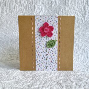 A single crocheted flower and leaf, with a hand stitched border. This small brown card has a blank white insert for your own message, and an envelope is included. Approximate size 10cm x 10 cm. Made using 100% cotton. Eco-friendly, Vegan friendly and fully recyclable.