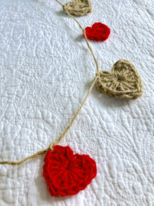 A garland of 9 individual hearts. x5 natural and x4 red. Hand crocheted and made in 100% jute. Approximate length 120cm.