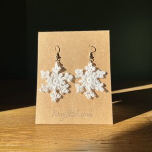 A handmade, crocheted pair of white snowflake earrings, made using 100% cotton and silver coloured metal fixings. The earring hooks are made from a silver plated brass and are nickel, lead and cadmium free. Each earring measures approximately 4cm wide by 4cm Height (excluding hook). No plastic has been used. This item is Vegan and Eco-friendly, reusable and fully recyclable.
