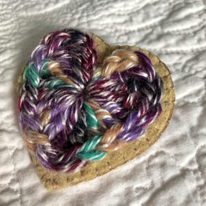 A crocheted heart on a hand stitched felt back with metal fixing brooch.