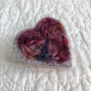 A crocheted heart on a hand stitched felt back with metal fixing brooch. Approximate size 5cm width x 5.5cm height.