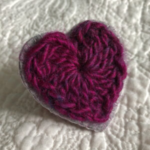 A crocheted heart on a hand stitched felt back with metal fixing brooch. Approximate size 6cm width x 6cm height.