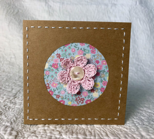 A single crocheted flower with hand stitched border on a small brown card (approximate size 10 x 10 cm)with blank white insert. Brown envelope included.