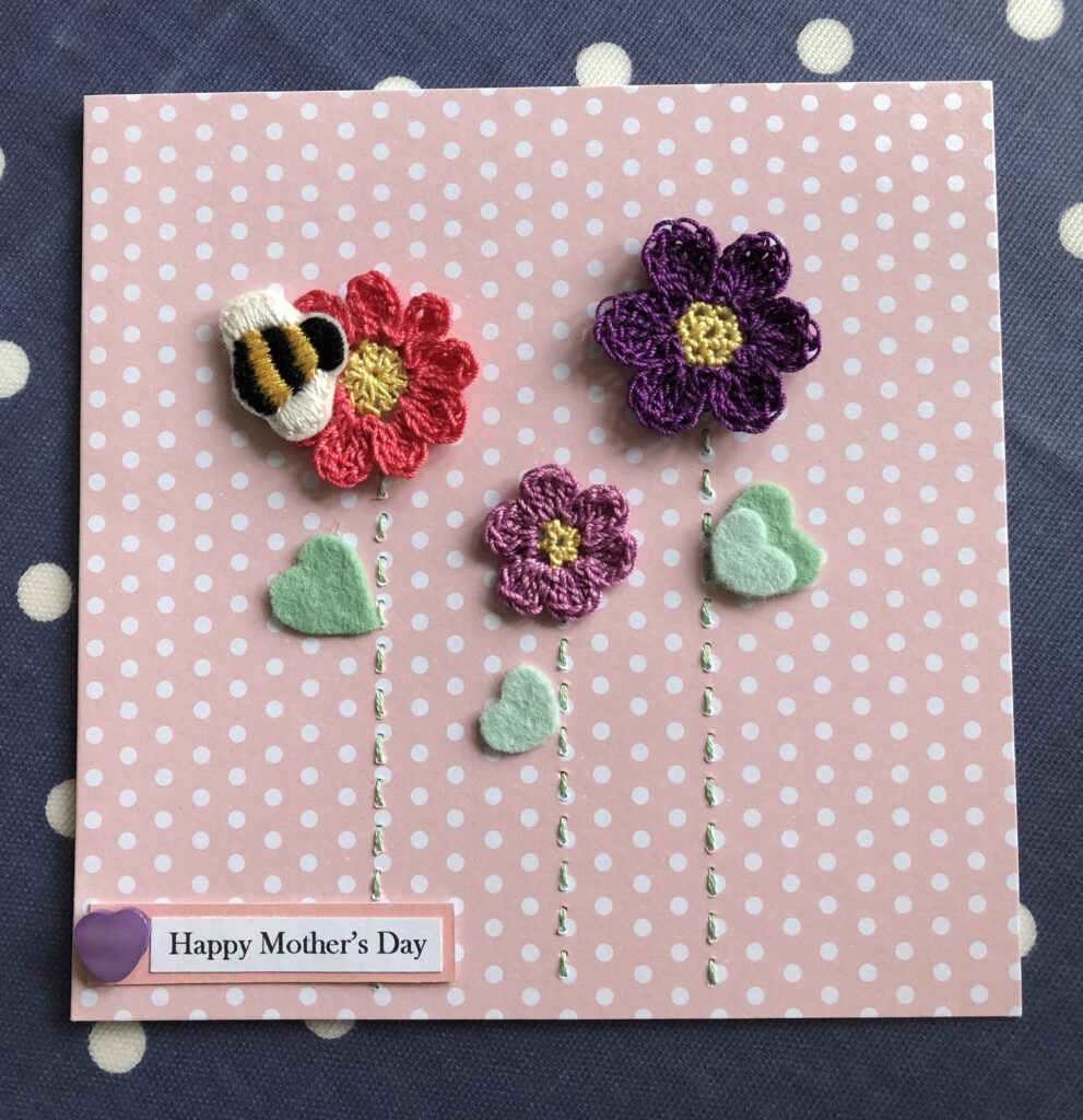 A hand embroidered and crocheted greetings card with bumble bee, flowers and a personalised tag.  