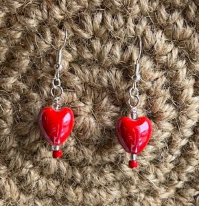A handmade pair of   red ceramic heart beaded earrings, made using a ceramic heart and glass beads with metal fixings. 

The earring hooks are made from a silver plated brass and are nickel, lead and cadmium free.

Each earring measures approximately 1.2cm wide by 4.5cm Height (including hook).
No plastic has been used. This item is Vegan and Eco-friendly, reusable and fully recyclable. 