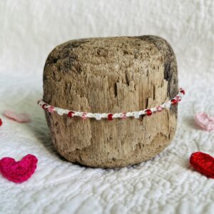 A handmade, crocheted, single stranded bracelet. Made using red, pink and cream pearlescent glass beads and 100% cream cotton with a fully adjustable sliding bead fastening. No plastic has been used. This item is Vegan and Eco-friendly, reusable and fully recyclable.