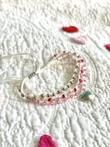 A handmade, crocheted and glass beaded bracelet with silver coloured metal heart charm. 

Fully adjustable with sliding glass bead fastening. 

3 strands, made using 100% cream cotton and glass beads in 3 colours of Red, Pink and silver. No plastic! 

Eco-friendly, vegan friendly and completely recyclable.