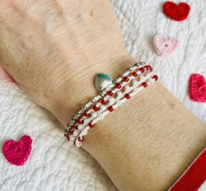 A handmade, crocheted and glass beaded bracelet with silver coloured metal heart charm. 

Fully adjustable with sliding metal bead fastening. 

4 strands, made using 100% cream cotton and glass beads in 3 colours of dark red, pearlescent cream and silver. No plastic! 

Eco-friendly, vegan friendly and completely recyclable.