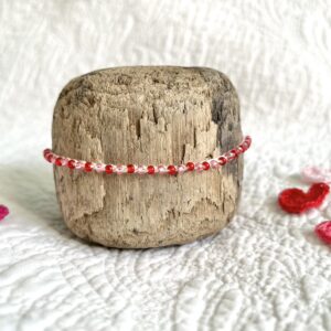 A handmade, crocheted, single stranded bracelet. Made using red and pink glass beads and 100% cream cotton with a fully adjustable sliding bead fastening. No plastic has been used. This item is Vegan and Eco-friendly, reusable and fully recyclable.
