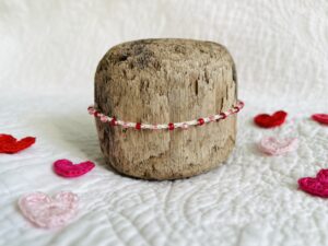 A handmade, crocheted, single stranded bracelet. Made using red and pink glass beads and 100% cream cotton with a fully adjustable sliding bead fastening.

No plastic has been used. This item is Vegan and Eco-friendly, reusable and fully recyclable. 