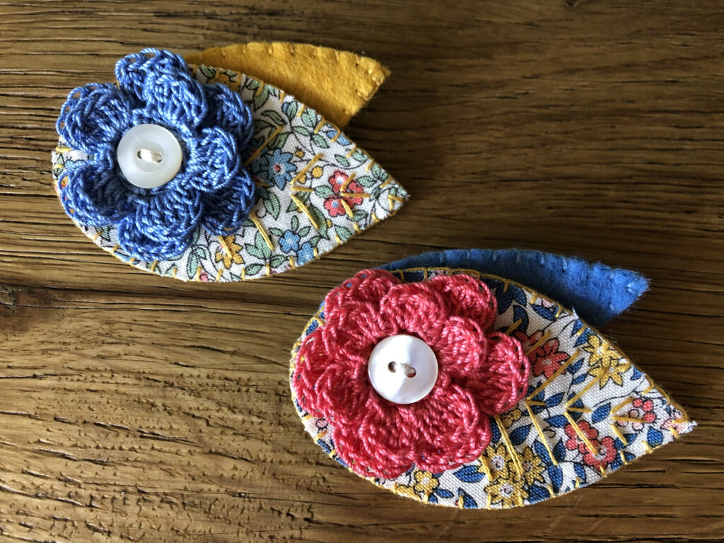 A single crocheted flower and two leaf brooch. Made using 100% Cotton flowers with hand stitched felt and fabric leaves.  