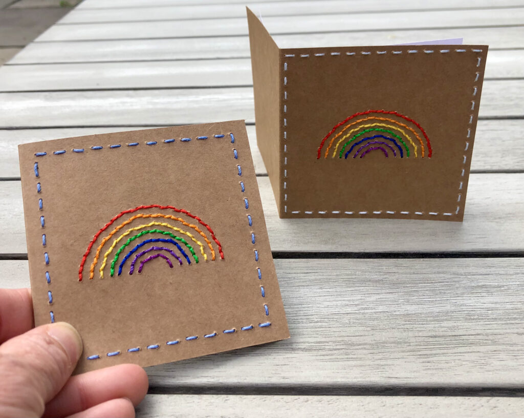A hand stitched rainbow greetings card. Left blank inside for your own message. 9cmX 9cm with envelope. made using 100% Cotton on brown card with a white paper insert. Eco-friendly and fully recyclable.