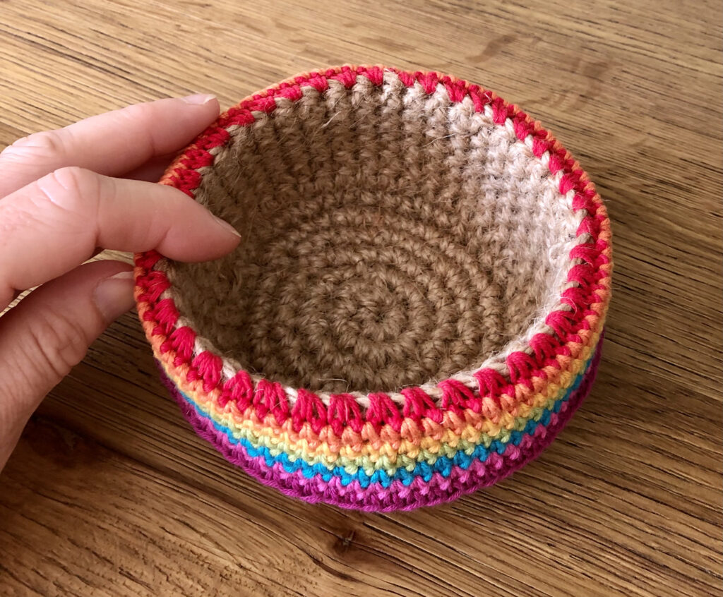 A handmade, crocheted, 100% jute basket, decorated with a 100% cotton rainbow edging. Approximate size 6.5cm Height x 12cm width.