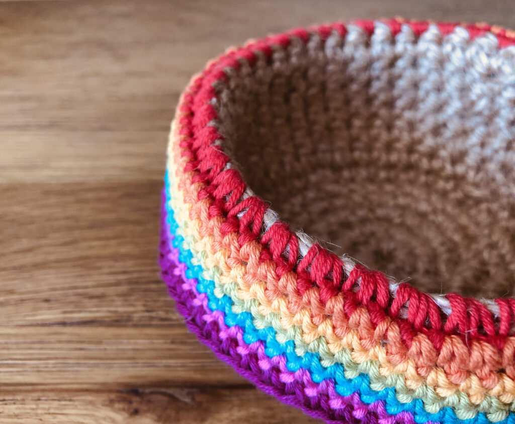A handmade, crocheted, 100% jute basket, decorated with a 100% cotton rainbow edging. Approximate size 6.5cm Height x 12cm width.