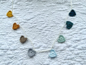 8 tiny crocheted hearts in a range of colours, Mustard to Teal. They are attached on a crocheted, natural cream cotton strand. Made in 100% cotton. Eco-friendly, vegan, recyclable, reusable. Total length approximately 60cm. Each heart measures approximately 2 x 2.5cm.