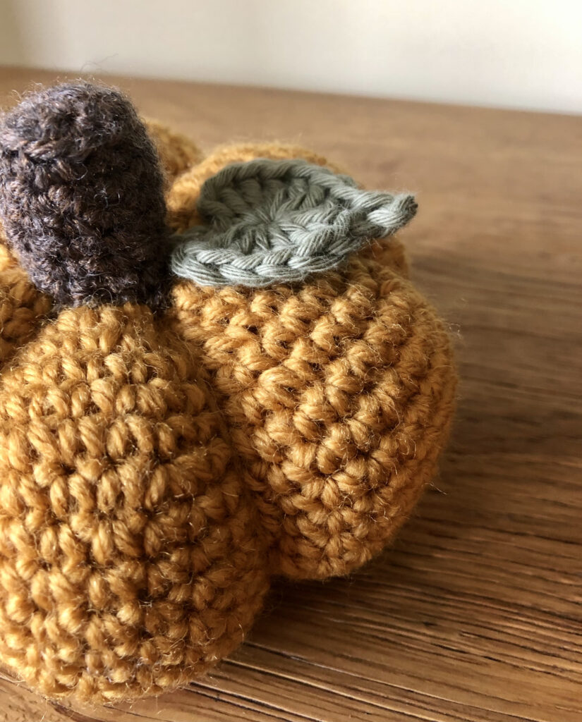 Mustard yellow coloured, crocheted pumpkin. Made using 100% wool, and with wool and cotton stalk and leaf details.