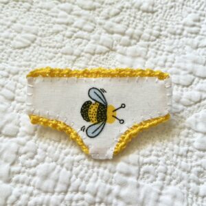 Handmade fabric and felt brooch with crocheted edging detail and a metal locking fastening. Approximate size 6cm Width x 4cm Height.