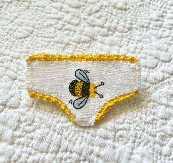 Handmade fabric and felt brooch with crocheted edging detail and a metal locking fastening. Approximate size 6cm Width x 4cm Height.