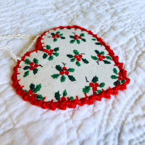 A hand-cut and hand stitched garland of 6 holly fabric and red felt hearts, with a red crocheted cotton edging detail. All fixed along a cream cotton string. Approximate length 125cm.