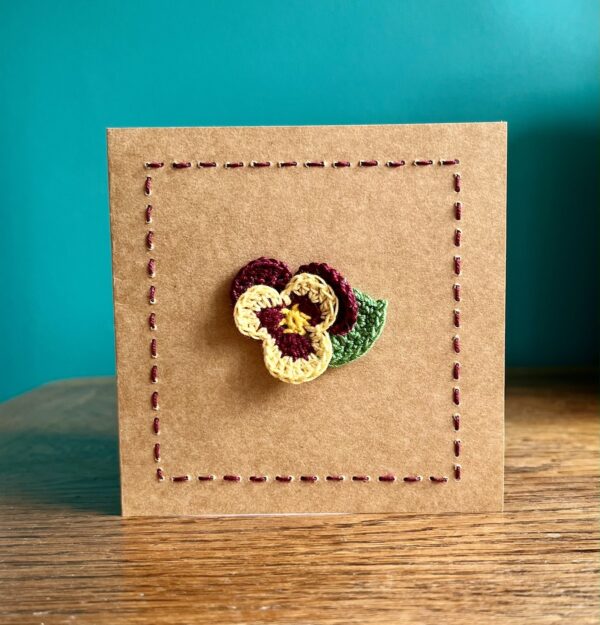 A single crocheted Burgundy and Yellow Pansy flower and a green leaf, with hand sewn boarder. This card has a blank white paper insert for you to write your own message. Handmade, using 100% cotton.