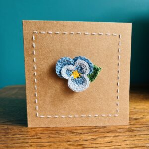 A single crocheted, two tone, light blue Pansy flower and a green leaf, with hand sewn boarder. This card has a blank white paper insert for you to write your own message. Handmade, using 100% cotton.