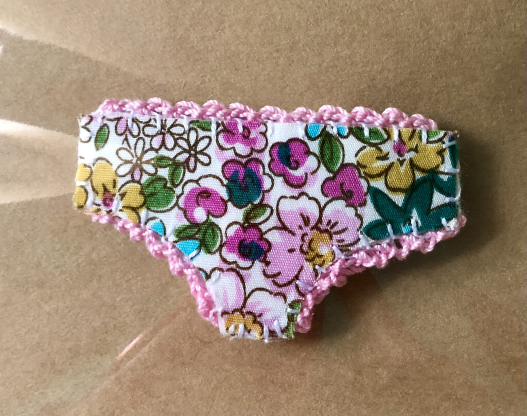 Handmade fabric and felt brooch with crocheted edging detail and a metal locking fastening. Approximate size 6cm Width x 4cm Height.