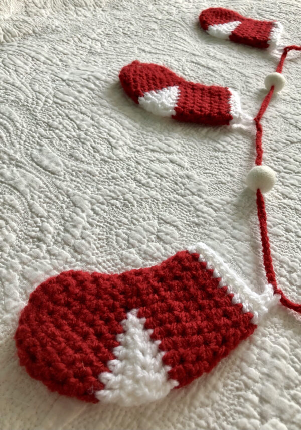 Garland of little Christmas stockings. 5 stockings with felt pom-pom details. Approximate length 125cm.